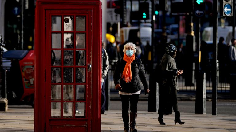 People wear face coverings as they walk through Westminster in central London. Pic: AP