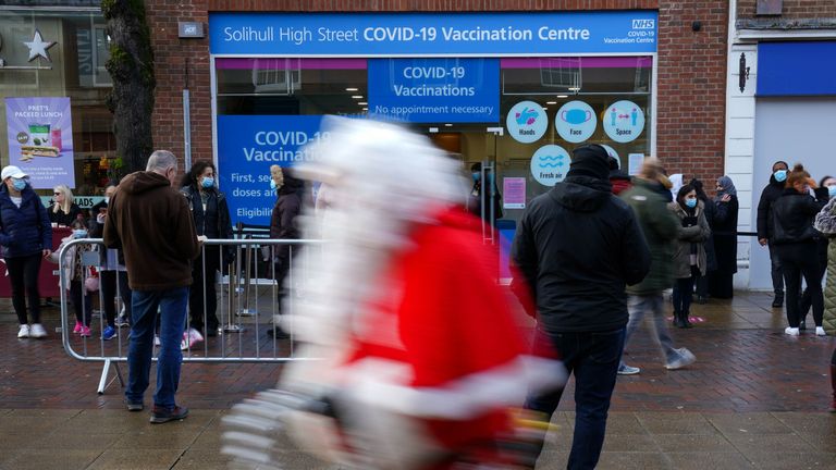 A Santa walks in front of a COVID vaccination centre in Solihull, West Midlands
