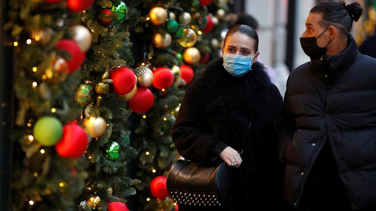 People walk past a store decorated for Christmas in central London