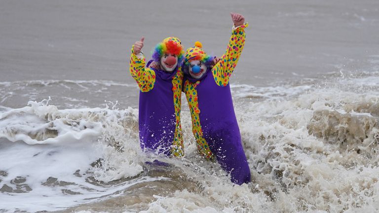 شناگران پری اسپرینگ گیت (سمت چپ) و کریس جانسون با لباس دلقک در فلیکس استو، سافولک، جایی که شیرجه کریسمس به دلیل آب و هوای بد لغو شد، وارد دریا می شوند.  تاریخ عکس: شنبه 25 دسامبر 2021