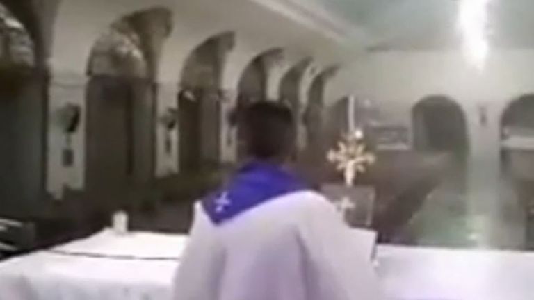 Priest conducts mass while typhoon batters church