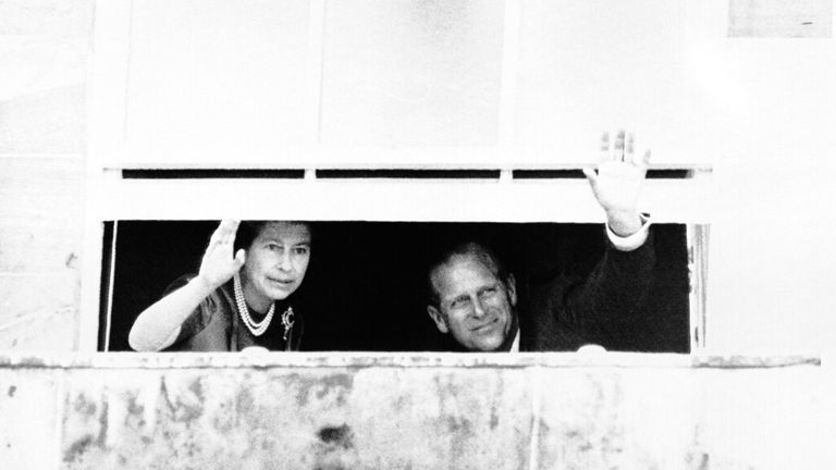 The Queen and Prince Philip wave at crowds through the window of Hillsborough Castle, Northern Ireland in August 1977. Pic: AP