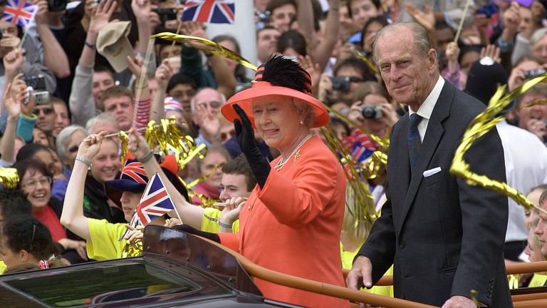 The Queen and Duke of Edinburgh wave at crowds in an open-top car down the Mall