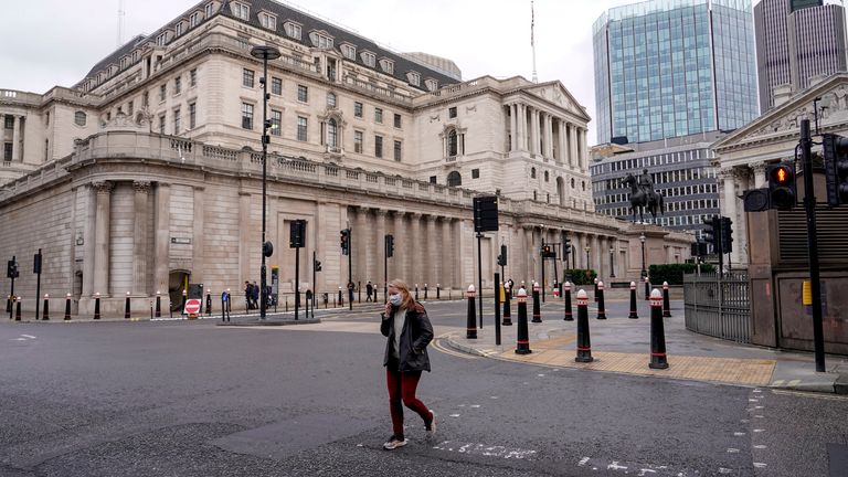 A person wears a face mask while walking crossing a road outside the Bank of England,  
Pic:AP