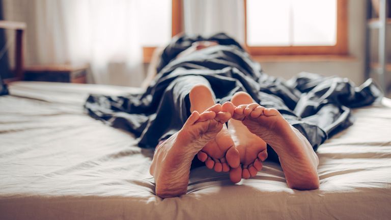Adult couple&#39;s feet looking out of bed


