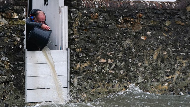 A person bails water from a property as sea water floods the shore line after high tide in Langstone, Hampshire, as Storm Barra hits the UK and Ireland with disruptive winds, heavy rain and snow on Tuesday. Picture date: Tuesday December 7, 2021.
