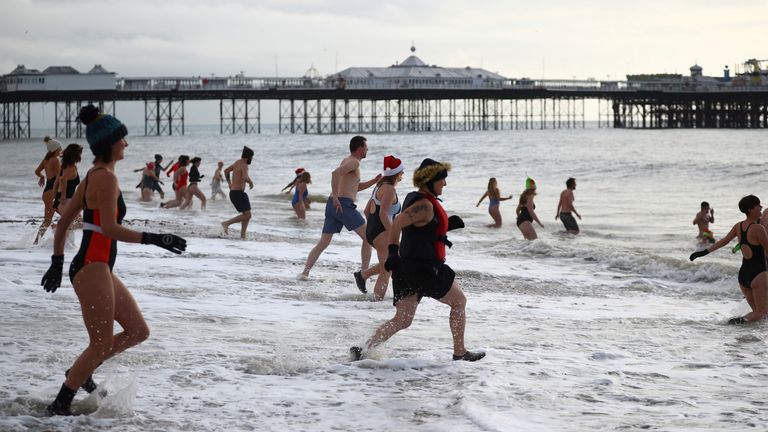 People enter the sea during a Christmas Day dip on Brighton beach in southern England, Britain, December 25, 2021. REUTERS/Hannah McKay
