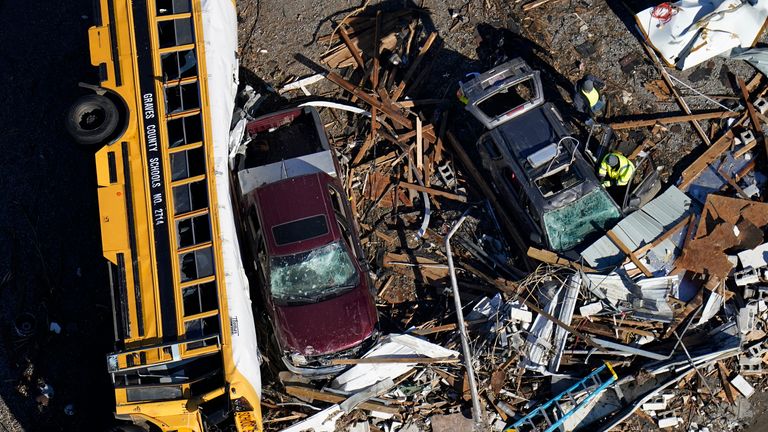 خدمات اورژانس در حال غربال کردن آوار در نزدیکی یک اتوبوس مدرسه ای واژگون شده در میفیلد، کنتاکی، پس از وقوع گردباد هستند.  عکس: AP