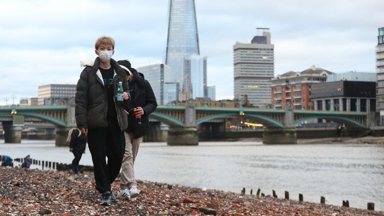 People walk along the River Thames in central London