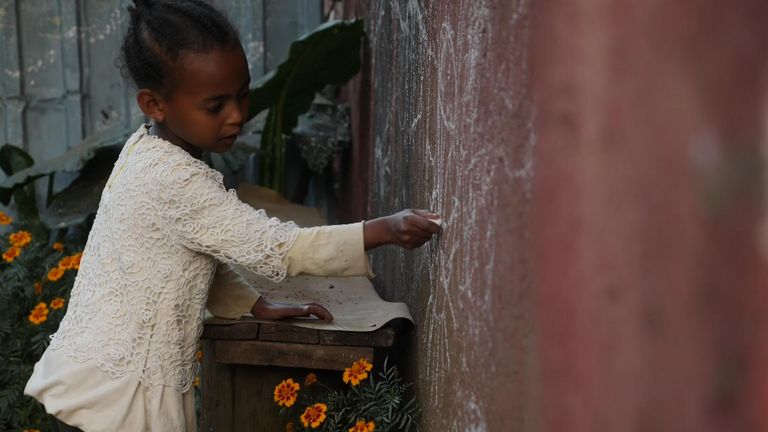 Kidist, 5 ans, dessine devant sa maison familiale en Éthiopie. 
