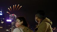 People wearing face masks watch fireworks as part of Hong Kong&#39;s New Year celebrations