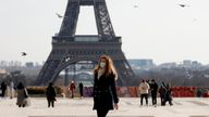 A woman, wearing protective face masks, walks in front of the Eiffel tower at the Trocadero in Paris amid the coronavirus disease (COVID-19) outbreak in France, February 11, 2021