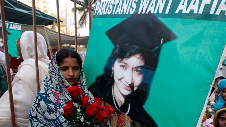 A Siddiqui supporter carries silk roses next to a poster during a celebration to mark her 41st birthday in Karachi in 2014