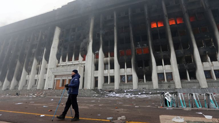 A man stands in front of the mayor&#39;s office building which was torched during protests triggered by fuel price increase in Almaty, Kazakhstan January 6, 2022. REUTERS/Pavel Mikheyev
