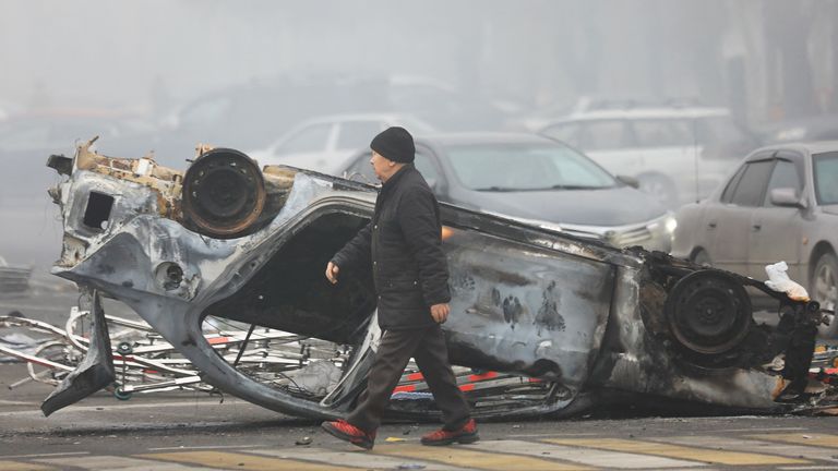 A man walks past a car that was burned during the protests triggered by fuel price increase in Almaty, Kazakhstan January 6, 2022. REUTERS/Pavel Mikheyev
