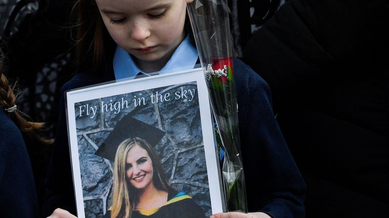 Une fille d'une garde d'honneur des enfants qu'une enseignante de 23 ans, Ashling Murphy, qui a été assassinée alors qu'elle faisait du jogging, enseignait à l'école nationale de Durrow regarde une photo de l'enseignante qu'elle tient pendant que les gens se rassemblent pour ses funérailles par le Église St Brigid à Mountbolus près de Tullamore, Irlande le 18 janvier 2022. REUTERS/Clodagh Kilcoyne