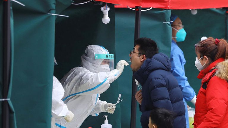 A medical worker collects a swab sample from a resident at a makeshift nucleic acid testing site at a residential compound, following new confirmed cases of the coronavirus disease (COVID-19), in Beijing, China January 24, 2022. REUTERS/Tingshu Wang