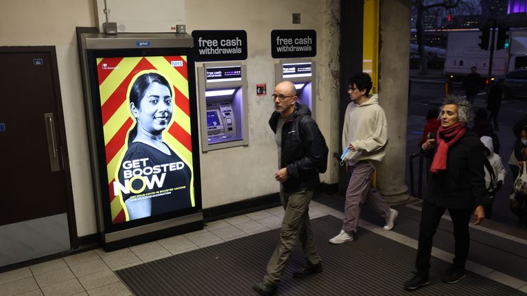 People walk through Embankment Station passing a get boosted advert, where it has been announced that no further coronavirus restrictions will be introduced before the new year. Picture date: Thursday December 30, 2021.