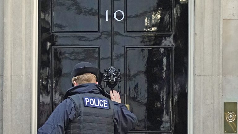 A police officer knocks on the door of the Prime Minister&#39;s official residence in Downing Street, Westminster, London, as public anger continues following the leak on Monday of an email from Boris Johnson&#39;s principal private secretary, Martin Reynolds, inviting 100 Downing Street staff to a &#34;bring your own booze&#34; party in the garden behind No 10 during England&#39;s first lockdown on May 20, 2020. Picture date: Wednesday January 12, 2022.
