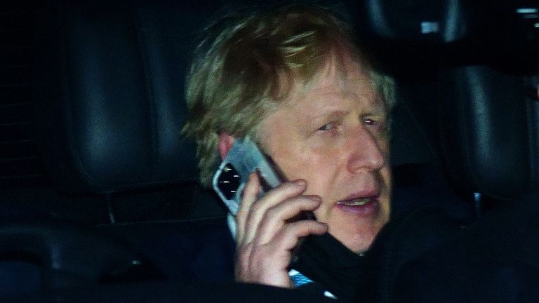 Boris Johnson in the back seat of a government car while speaking on a mobile phone as he returns to Downing Street