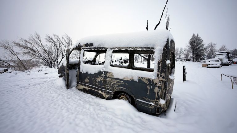 The remains of a van destroyed by wildfires before heavy snow fell. Pic: AP