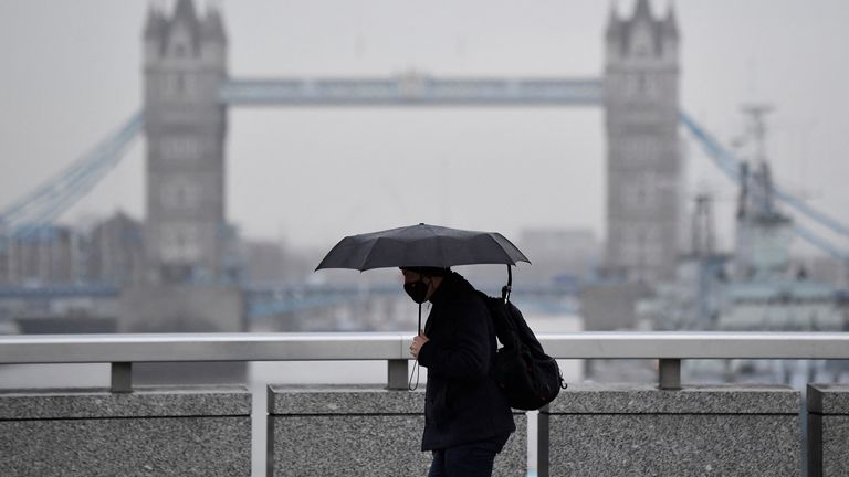 A worker wears a protective face mask as he crosses London Bridge, with Tower Bridge seen behind, during the morning rush-hour, as coronavirus disease (COVID-19) lockdown guidelines imposed by British government encourage working from home, in the City of London financial district, Britain, January 4, 2022. REUTERS/Toby Melville
