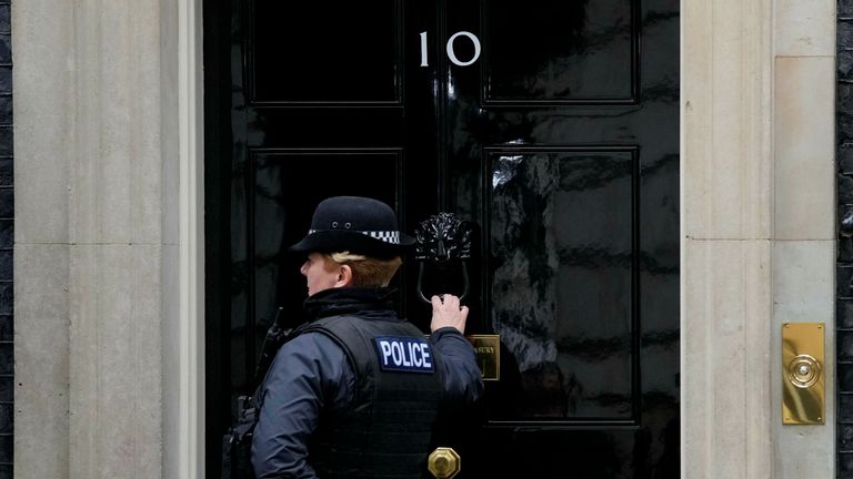 یک افسر پلیس درب خیابان داونینگ 10 در لندن را می زند، سه شنبه، 11 ژانویه 2022. پلیس در ارتباط با ادعاهایی که دستیار نخست وزیر سازماندهی کرده است با کابینه در تماس است. "الکل خود را بیاورید" یک مهمانی نوشیدنی در خیابان داونینگ در ماه مه 2020 در طول اولین محاصره ویروس.  (عکس AP / فرانک آگستاین)