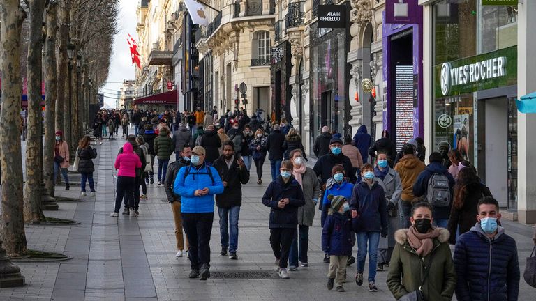 Des personnes portant des masques faciaux marchent le long des Champs Elysées à Paris
