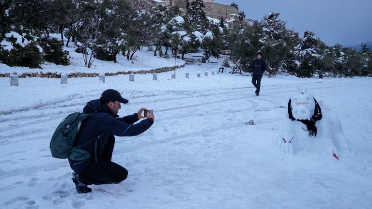 Un homme prend une photo devant l'ancienne colline de l'Acropole, après une tempête de neige, le mardi 25 janvier 2022. Une tempête de neige d'une rare gravité a perturbé le trafic routier et aérien lundi dans la capitale grecque d'Athènes et la Turquie voisine la plus grande ville d'Istanbul, tandis que la majeure partie de la Grèce, y compris - exceptionnellement - plusieurs îles de la mer Égée, et une grande partie de la Turquie étaient recouvertes de neige.  (AP Photo/Thanassis Stavrakis) PIC: AP