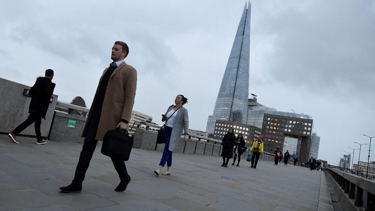 Workers cross London Bridge, with The Shard skyscraper seen behind, during the morning rush-hour, as the coronavirus disease (COVID-19) lockdown guidelines imposed by British government encourage working from home, in the City of London financial district, London, Britain, January 4, 2022. REUTERS/Toby Melville
