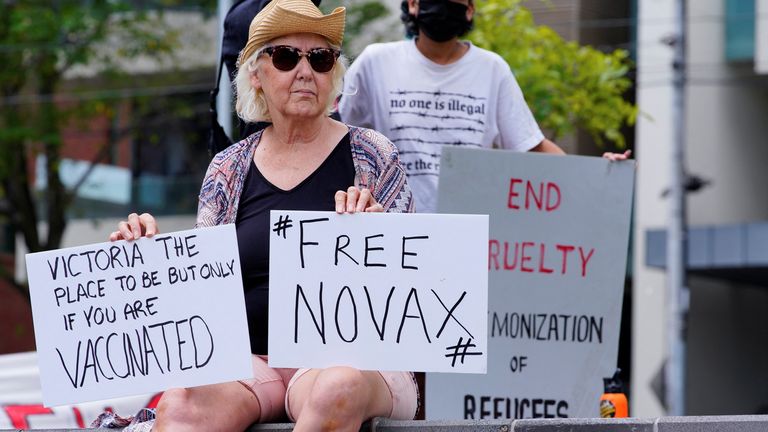 A protestor holds signs outside Park Hotel, where Serbian tennis player Novak Djokovic is believed to be staying