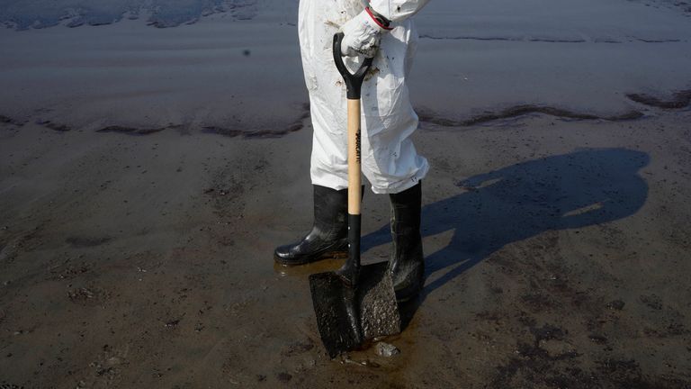 کارگران پالایشگاه نفت محلی در حال تمیز کردن ساحل هستند.  عکس: AP