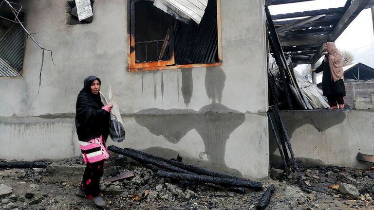 A Pakistani Kashmiri collects belongings after homes were reportedly destroyed by Indian shelling in 2020