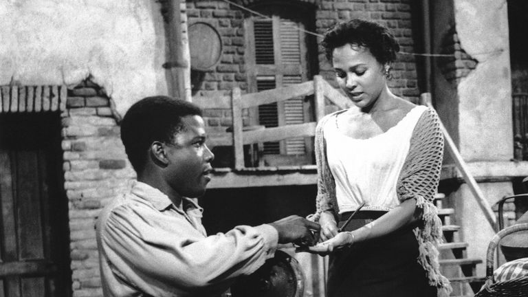 Kneeling on his crippled legs, Porgy, played by Sidney Poitier, urges Bess (Dorothy Dandridge, center) to join Maria (Pearl Bailey) at the picnic which was to change their lives, in this scene from the movie version of “Porgy and Bess” in character on Nov. 17, 1958. (AP Photo)


