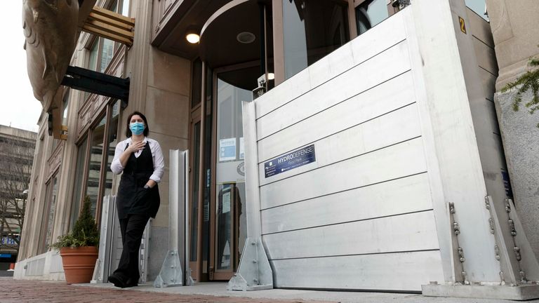 A waitress stands in front of a flood barrier at the entrance to a restaurant on Friday. Pics: AP