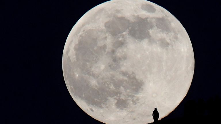 A person stands on the hillside of Glastonbury Tor as they watch the full moon, sometimes known as a "Wolf Moon", rise, as viewed from Glastonbury, Britain, January 17, 2022. REUTERS/Toby Melville

