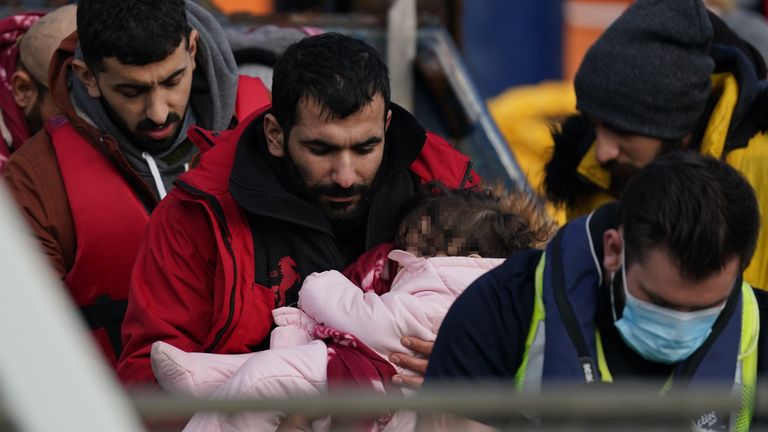  A man thought to be migrants carries a small child after they were brought in to Dover, Kent, following a small boat incident in the Channel. Picture date: Tuesday January 4, 202