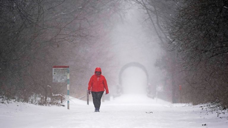 A man walks on the Monon Trail as snot blows, Thursday, Feb. 3, 2022, in Indianapolis.  A major winter storm with millions of Americans in its path is spreading rain, freezing rain and heavy snow further across the country. (AP Photo/Darron Cummings) 