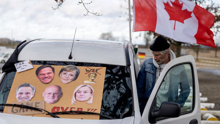 A Canadian flag flaps in the wind on a car with a placard of former and present world leaders on the windshield at a car park outside the centre of Brussels. Pic: AP