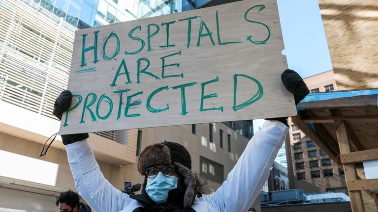 A medical staff member holds up a sign at a rally in support of healthcare workers outside Toronto General Hospital, as truckers and supporters protest coronavirus disease (COVID-19) vaccine mandates, in Toronto, Ontario, Canada, February 5, 2022. REUTERS/Chris Helgren REFILE - CLARIFYING INFORMATION

