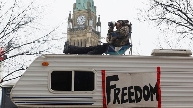 A man sits on top of a camper in front of Parliament Hill during protests in Ottawa