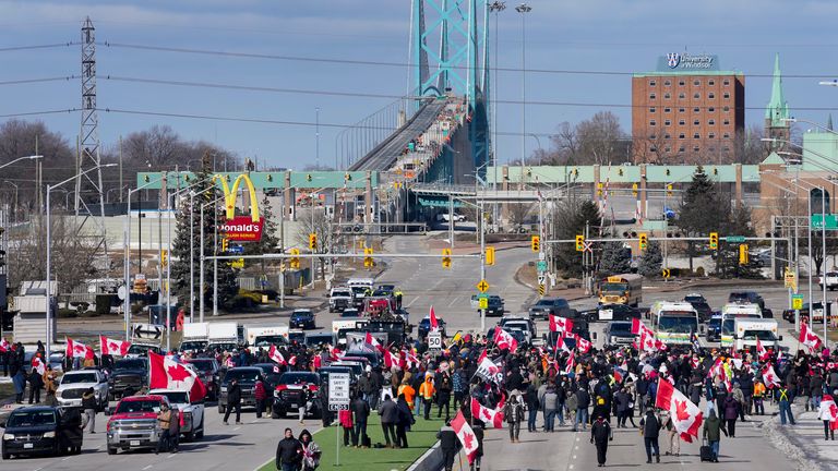 Police officers hold a line as protesters support the truckers as the police enforce an injunction against their demonstration, which has blocked traffic across the Ambassador Bridge by protesters against COVID-19 restrictions, in Windsor, Ont., Saturday, Feb. 12, 2022. THE CANADIAN PRESS/Nathan Denette