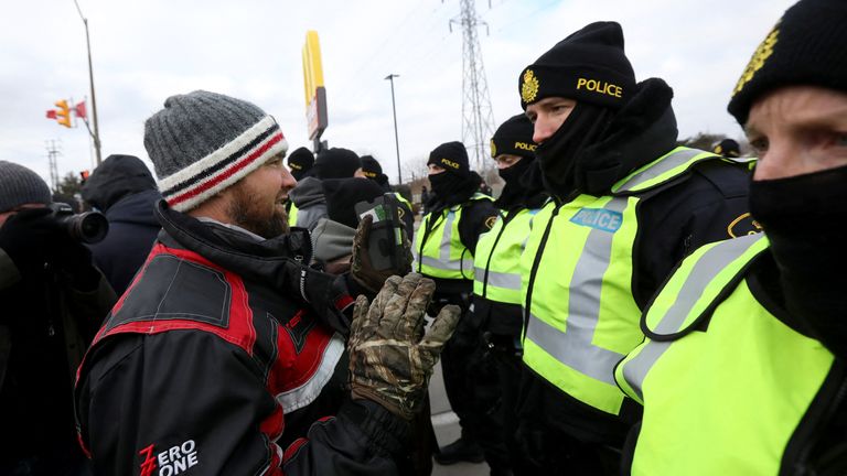 A protester interacts with police officers, who stand guard on a street after Windsor Police said that they are starting to enforce a court order to clear truckers and supporters who have been protesting against coronavirus disease (COVID-19) vaccine mandates by blocking access to the Ambassador Bridge, which connects Detroit and Windsor, in Windsor, Ontario, Canada February 12, 2022. REUTERS/Carlos Osorio