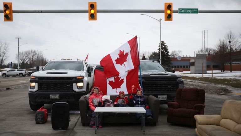 Children sit on a sofa placed on a blocked road as the Ambassador Bridge, which connects Detroit and Windsor, stands effectively shut down after truckers and their supporters blocked it in protest against coronavirus disease (COVID-19) vaccine mandates, in Windsor, Ontario, Canada February 10, 2022. REUTERS/Carlos Osorio