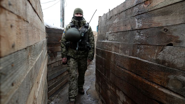 A member of the Ukrainian State Border Guard Service walks in a trench at the Kliusy checkpoint near the frontier with Russia in the Chernihiv region, Ukraine February 16, 2022. REUTERS/Valentyn Ogirenko
