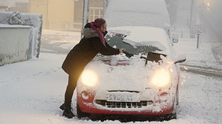 A woman clears snow from her car in Tow Law, County Durham, as Storm Eunice sweeps across the UK after hitting the south coast earlier on Friday. With attractions closing, travel disruption and a major incident declared in some areas, people have been urged to stay indoors. Picture date: Friday February 18, 2022.