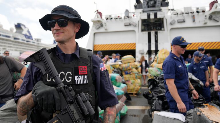 A member of the U.S. Coast Guard stands watch as the Coast Guard and other agencies prepare to unload more than one billion dollars worth of seized drugs from Coast Guard Cutter James at Port Everglades, Thursday, Feb. 17, 2022, in Fort Lauderdale, Fla. The Coast Guard said the haul included approximately 54,500 pounds of cocaine and 15,800 pounds of marijuana from multiple interdictions in the Caribbean Sea and the eastern Pacific. (AP Photo/Rebecca Blackwell)