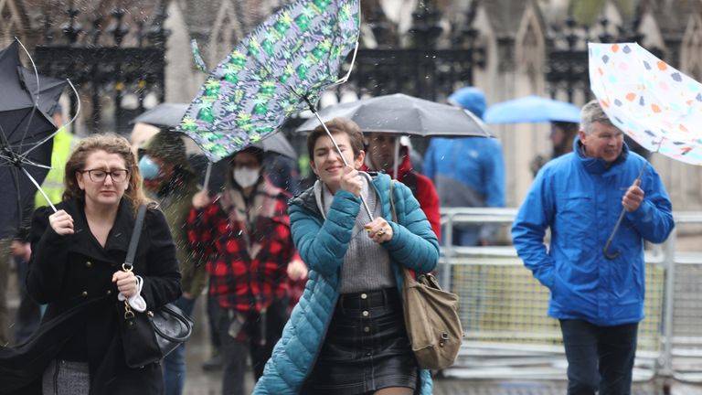 Members of the public brace the wind and wet weather in Westminster central London following Storm Eunice. Picture date: Friday February 18, 2022.