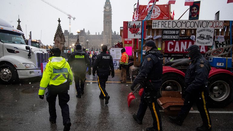 Police walk through parked trucks to make an arrest on Wellington Street, on the 21st day of a protest against COVID-19 measures that has grown into a broader anti-government protest, in Ottawa, on Thursday, Feb. 17, 2022. THE CANADIAN PRESS/Justin Tang