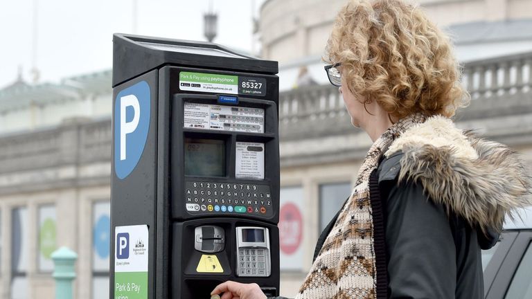 Woman paying for parking with one pound coin on Brighton seafront UK